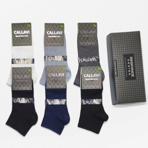 Six pairs of men's socks in neutral colors displayed, with quality packaging and a stylish black box.