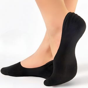 Close-up of a foot wearing a black, low-cut sock, showcasing its sleek design and comfort, against a light background.