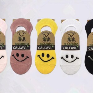 Five pairs of colorful bamboo socks with smiley faces in pink, mauve, yellow, white, and black, displayed on a white background.