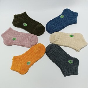 six pairs of colorful fuzzy socks arranged in a star pattern on a white background.