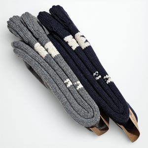 The two pairs of alpaca socks, one gray and the other navy blue, are neatly arranged sideways on a light surface, highlighting their extra thickness'