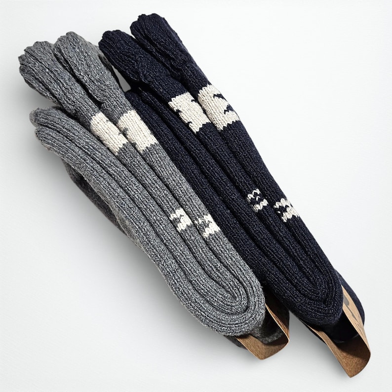 The two pairs of alpaca socks, one gray and the other navy blue, are neatly arranged sideways on a light surface, highlighting their extra thickness'