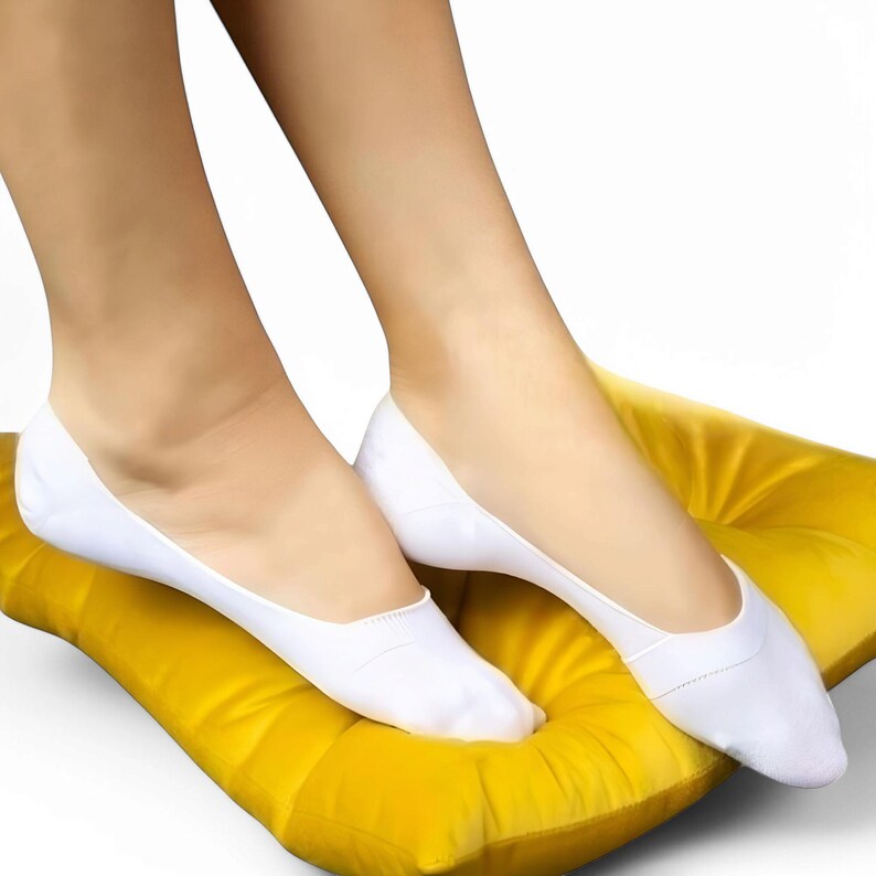 A pair of feet in white socks resting on a cushioned yellow pillow, highlighting comfort and relaxation.