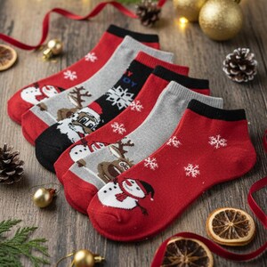Festive Christmas ankle socks featuring snowman, reindeer, and Santa designs on a wooden table with holiday decorations like pine cones, gold ornaments, dried orange slices, and red ribbon