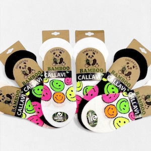 May include: Four pairs of white, black, and pink socks with a smiley face pattern. The socks are packaged in clear plastic bags with a cardboard header that says "SNEAKERS BAMBOO CALLAVI".