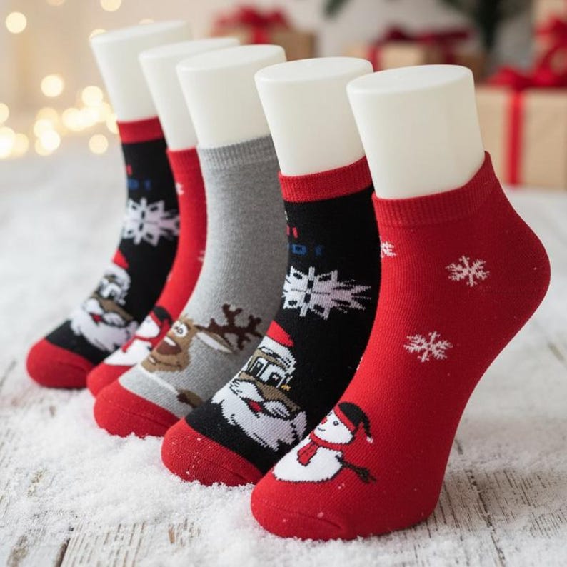 Five pairs of festive christmas socks displayed on mannequins, featuring Santa, a snowman, reindeer, and snowflakes, set against a holiday backdrop between artifical snow.