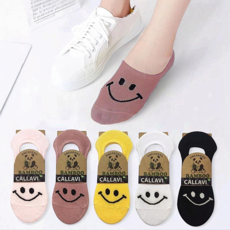Colorful bamboo sneakers socks with smiley faces, shown in pink, brown, yellow, white, and black, paired with white sneakers.