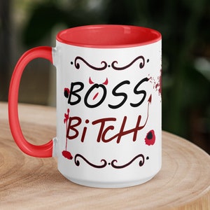 Puede incluir: Taza de cerámica blanca con borde y asa rojos. La taza tiene un gráfico negro y rojo que dice "Boss Bitch" con cuernos de diablo y una cola.