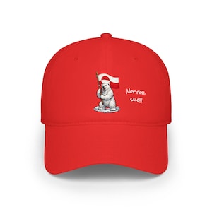 Puede incluir: Una gorra de béisbol roja brillante con un oso polar de dibujos animados sosteniendo una bandera. El oso está sobre un parche nevado, y el texto "NOT FOR SALE!!!" está en el lateral. La gorra tiene una visera curva y un botón en la parte superior.