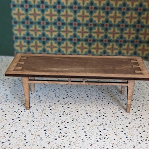 May include: A wooden coffee table with a dark brown finish and a simple, rectangular design. The table has four legs and a slightly raised edge around the top.