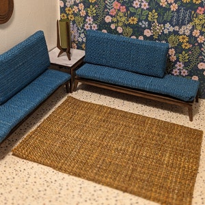 May include: Two blue fabric sofas with wooden frames and a brown woven rug on a white tiled floor.