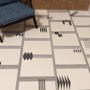 May include: A miniature blue upholstered chair with a dark wooden frame sits on a patterned floor. The floor features a repeating geometric design in black and white, with rectangular shapes and abstract motifs.