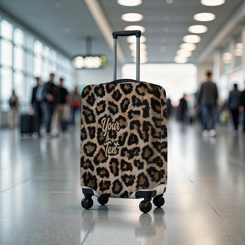 Pode incluir: Uma mala com rodas com estampa de leopardo. A mala tem uma al&ccedil;a retr&aacute;til e quatro rodas pretas. O texto "Your Text" &eacute; exibido na frente em uma fonte cursiva. O fundo &eacute; um terminal de aeroporto desfocado.