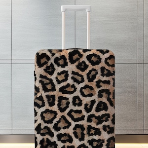 Pode incluir: Uma mala com rodas e al&ccedil;a retr&aacute;til. A mala &eacute; coberta por um padr&atilde;o de leopardo marrom e preto. O fundo &eacute; uma parede cinza claro.