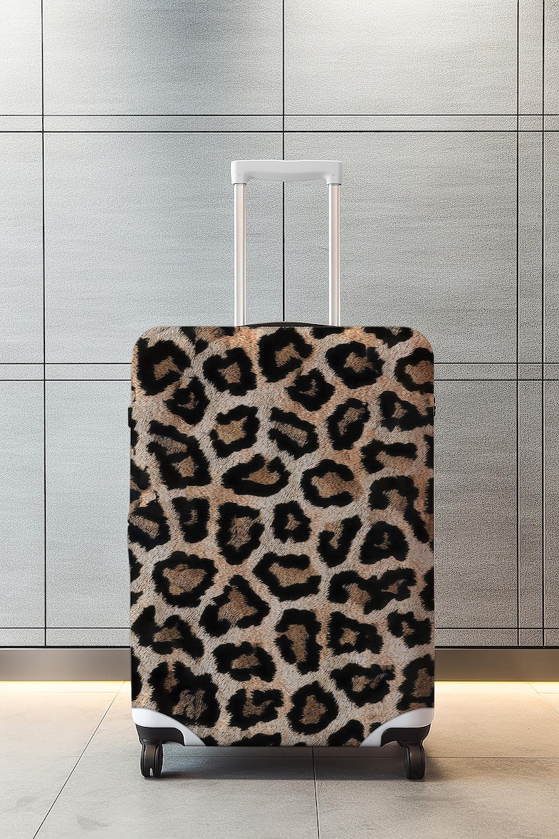 Pode incluir: Uma mala com rodas e al&ccedil;a retr&aacute;til. A mala &eacute; coberta por um padr&atilde;o de leopardo marrom e preto. O fundo &eacute; uma parede cinza claro.
