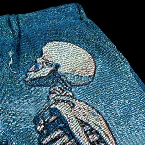 May include: A blue tapestry with a white skeleton design. The skeleton is depicted in a standing pose with its arms raised.