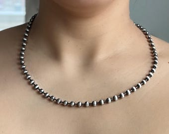 May include: A silver chain necklace with small round beads.