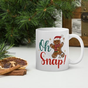 May include: White ceramic mug with a gingerbread man graphic and the text "Oh Snap!" in red and green lettering.
