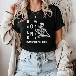 May include: Black t-shirt with a white skeleton graphic and the text "HOW OLD I OVERTHINK THIS".
