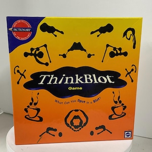 May include: A boxed ThinkBlot game with a gradient orange and yellow background. The box features black inkblot designs and the game title. The text "What Can You Spot in a Blot?" is also visible.