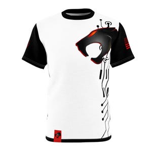 Puede incluir: Camiseta blanca con mangas y cuello negros. Presenta un gráfico de cabeza de pantera negra con detalles en rojo y un diseño de placa de circuito. La manga derecha tiene una pequeña bandera estadounidense.
