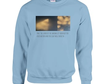 May include: Light blue sweatshirt with a quote about shadows and light. The quote reads: "Don't be scared of the shadows let them help you focus within and the light will shine in."