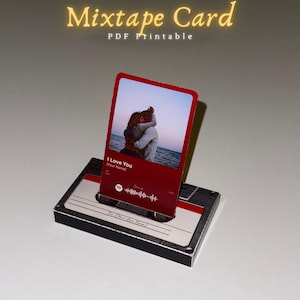 May include: A red Mixtape Card with the text "I Love You" and a photo of a couple hugging. The card is displayed on a cassette tape-shaped holder. The words "Mixtape Card PDF Printable" are written at the top.