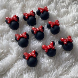 Puede incluir: Diez encantos en forma de cabeza de Minnie Mouse de color negro y rojo con lunares blancos. Los encantos están hechos de arcilla polimérica y miden aproximadamente 2,5 cm.