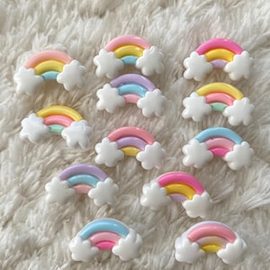 Può includere: Una collezione di 12 ciondoli arcobaleno e nuvola in tonalità pastello. I ciondoli sono in plastica e hanno una finitura lucida. Sono perfetti per aggiungere un tocco di fantasia a lavoretti, gioielli e altri progetti.