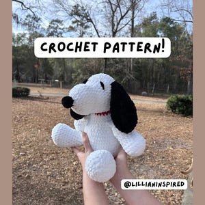 May include: A white crochet Snoopy plush toy with black ears and a black nose, wearing a red collar. The text "CROCHET PATTERN!" is displayed above the toy. The toy is held in front of a blurred outdoor background.