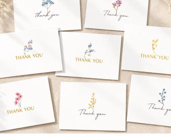 May include: A collection of eight white rectangular thank you cards, each featuring a small watercolour illustration of a different wildflower sprig. The text Thank you is printed in either a black script font or a gold serif font on each card.
