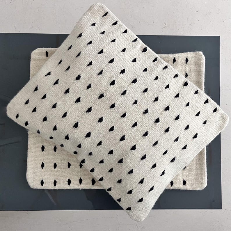 Studio CM | A cream colored wool pillowcase that has black dots made in Oaxaca Mexico by hand
