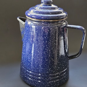 May include: Blue enamel coffee pot with a speckled finish and a lid. The pot has a handle and a spout.