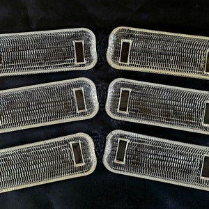 May include: Six clear plastic rectangular trays with a textured surface. The trays have a rectangular opening in the center.