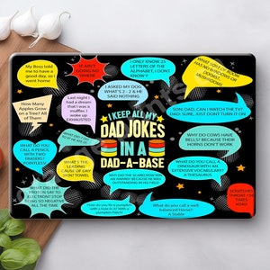 May include: Black and white cutting board with colorful speech bubbles containing dad jokes. The board features a variety of jokes, including "What do you call a pencil with two erasers? Pointless!" and "Why did the scarecrow win an award? Because he was outstanding in his field."