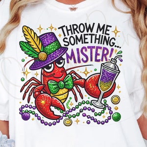 May include: A white t-shirt featuring a cartoon crawfish wearing a purple and green Mardi Gras hat and holding a purple and gold cocktail. The crawfish is surrounded by green, purple, and gold beads and the text "Throw me something... Mister!" is printed on the shirt.