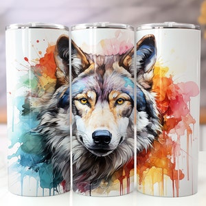 Op de afbeelding: Drie roestvrijstalen bekers met een aquarelontwerp van een wolvenkop. De vacht van de wolf is grijs en bruin, en de achtergrond is een mix van blauw, groen, geel en oranje.