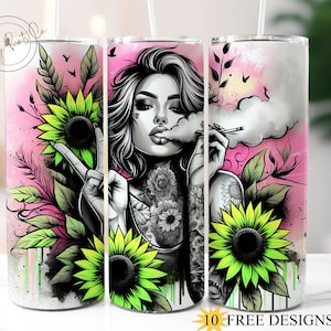 May include: A white tumbler with a pink background and a colorful graphic of a woman with tattoos, sunflowers, and smoke. The woman is holding a cigarette in her hand and has a peace sign with her other hand. The text "10 FREE DESIGNS" is at the bottom of the image.