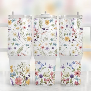 May include: Three stainless steel tumblers with a white background and a floral pattern in shades of pink, yellow, blue, and green. The tumblers have a handle and a lid.