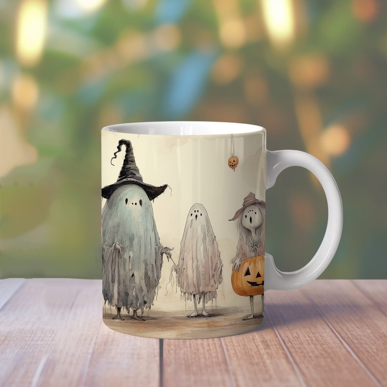 May include: White ceramic mug with a Halloween-themed design featuring four ghosts dressed in costumes. The ghost on the left is wearing a witch's hat, the ghost in the middle is holding a small pumpkin, and the ghost on the right is holding a larger pumpkin.