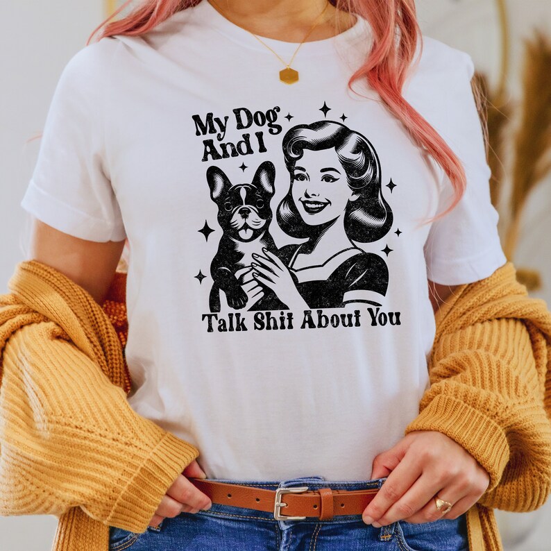 Może przedstawiać: Biała koszulka z czarno-białym obrazkiem kobiety trzymającej buldoga francuskiego. Tekst na koszulce brzmi "My Dog And I Talk Shit About You."