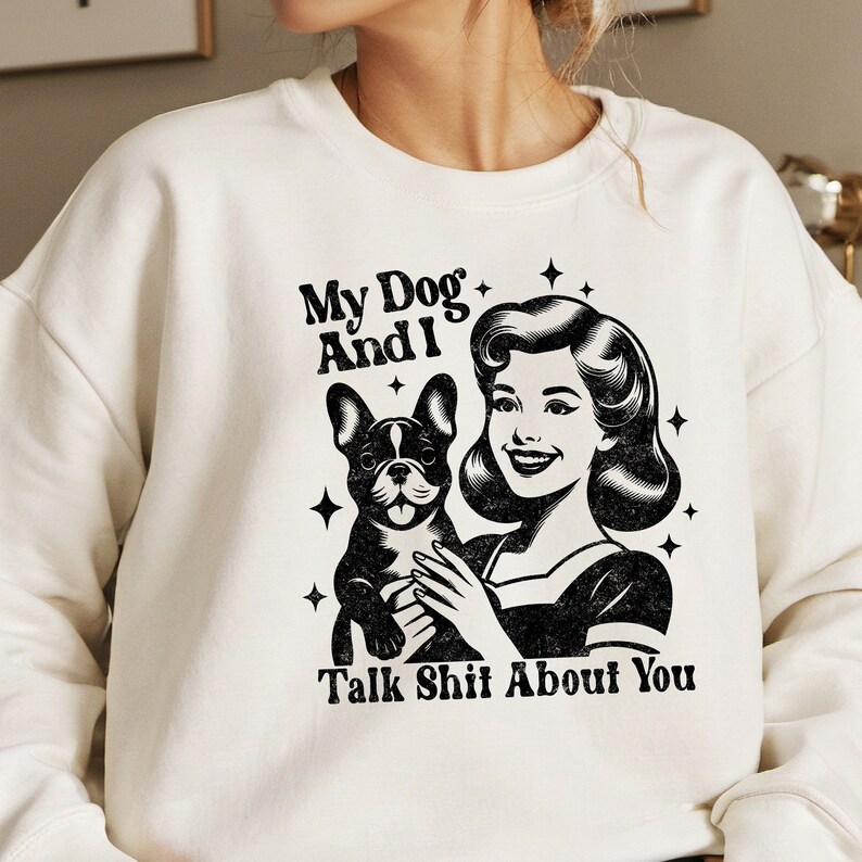 Może przedstawiać: Biała bluza z czarno-białym nadrukiem przedstawiającym kobietę trzymającą buldoga francuskiego. Na bluzie widnieje napis "My Dog And I Talk Shit About You".
