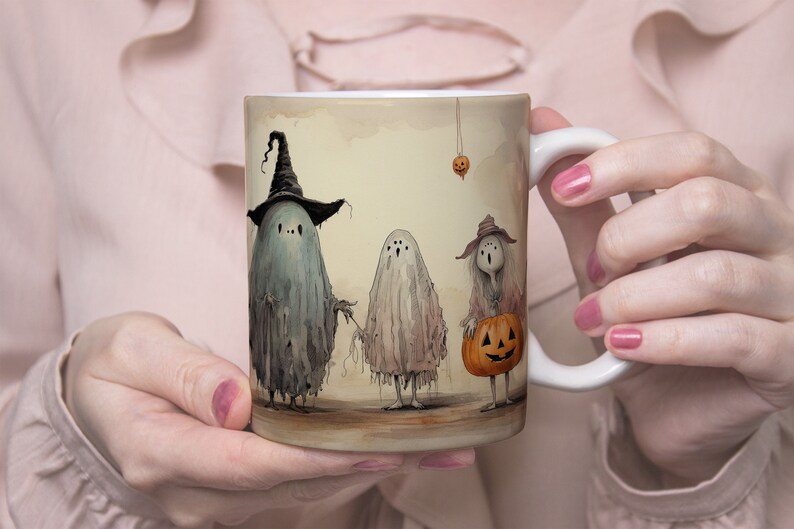 May include: A white ceramic mug with a Halloween-themed design. Three ghosts are depicted, one wearing a witch's hat, another holding a stick, and the third carrying a jack-o'-lantern. The background is a light brown with a vintage look.