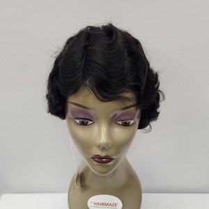 May include: A dark brown wig with a short, wavy style. The wig is on a mannequin head with a light brown skin tone. The wig is labeled "Hairmaze".