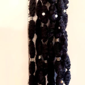 Può includere: Dreadlocks neri con accenti argentati e perle. I dreadlocks sono lunghi circa 53 cm. L'accessorio per capelli è adornato con piccole perline d'argento e perle bianche, creando un look unico ed elegante.