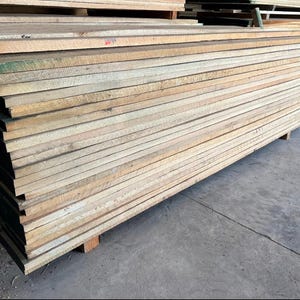May include: A stack of light brown wooden planks, likely for construction or woodworking projects.