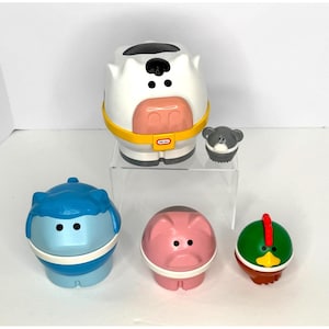 May include: A collection of Little Tikes animal-shaped toys. Includes a white cow with a yellow band, a blue hippo, a pink pig, a green duck, and a gray bear. The toys are designed for young children.