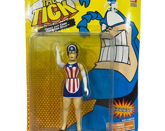 May include: A plastic action figure of a woman in a red, white, and blue American Maid costume. The figure is holding a white glove in her right hand and is standing on a yellow and black polka dot background. The figure is packaged in a clear plastic blister pack with a yellow and black background. The packaging features the words "The Tick" and "Twist and Chop American Maid" in black text. The packaging also features a blue and white illustration of a superhero with a large, toothy grin.
