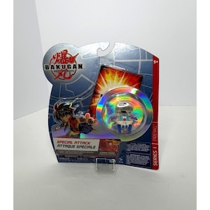 May include: Bakugan Series 1 Preyas Special Attack toy in its original packaging. The packaging features a holographic bubble with the toy inside, along with a cartoon illustration of a character. The text "Bakugan" is prominently displayed.