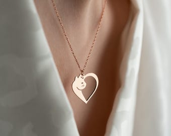 May include: A rose gold necklace with a heart-shaped pendant featuring a cat silhouette.